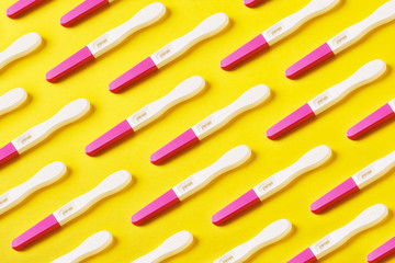 positive pregnancy tests pattern over yellow background, awaiting the birth of a girl