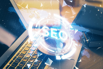 Double exposure of table with computer and seo drawing hologram. Search optimization concept.