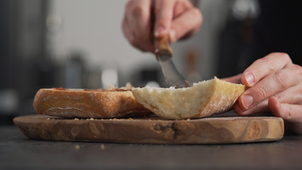 man spreading fig jam on ciabatta on olive board