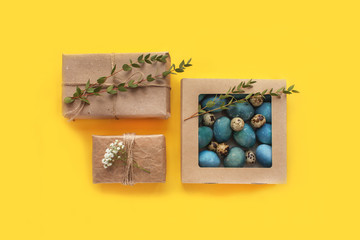 Easter composition border with empty paper blank, colored eggs, cotton flowers, gift box and leaves on blue background. Happy Easter sale or greeting concept.