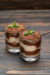 Classic tiramisu dessert in a glass cup on wooden background