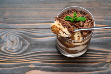 Classic tiramisu dessert in a glass cup on wooden background