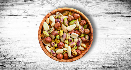 Nuts Mixed in a wooden white board.Variety of Walnuts, Almonds, Hazelnuts, Cashews, Pistachios. Concept of Healthy raw food selective focus.