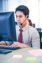 Young customer service men agent with headsets and computer working at office.
