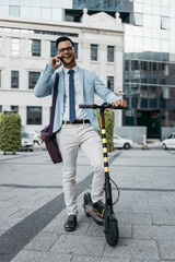 Young modern man using and driving electric scooter on city street. Modern and ecological transportation concept.