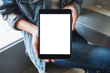 Mockup image of a woman holding and showing black tablet pc with blank white screen in cafe