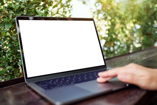 Mockup image of a woman using and touching on laptop touchpad with blank white desktop screen in the outdoors