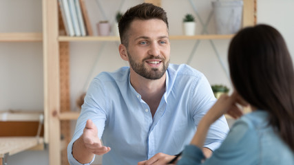 Young man involved in conversation with colleague in office