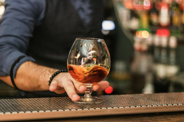 hand holding a glass of whiskey at the bar