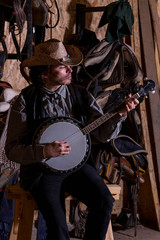 Portrait of a cowboy in a stable, playing the banjo