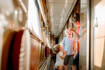 Three children play a train, family travel. two girls blondes younger brother.children games in the carriage, laugh and rejoice, brotherly love