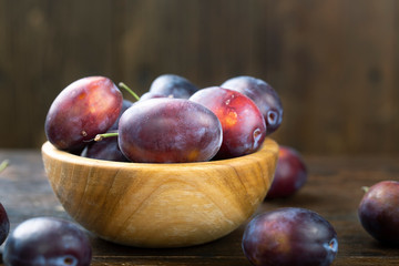 Ripe plums in a wooden bowl. Fresh fruits.