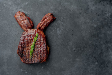 Grilled Easter steak with spices. Easter bunny on stone background with copy space for your text.