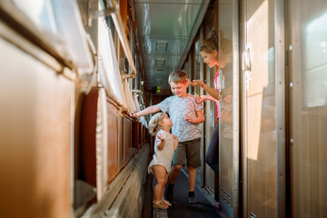 Three children play a train, family travel. two girls blondes younger brother.children games in the carriage, laugh and rejoice, brotherly love