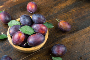 Ripe plums in a wooden bowl. Fresh fruits.