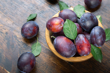 Ripe plums in a wooden bowl. Fresh fruits.