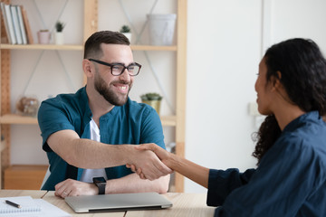 Smiling hr manager shaking hands with african american job applicant.
