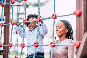 Mother and young kid son african black race play together at the playground park having fun and...