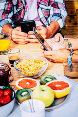 Close up of people with connected modern smart phone during breakfast sit on the table - fresh and tasty coloured fruits and italian espresso coffee for healthy lifestyle