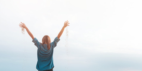 Happy woman in desert with raised hands full of sand, copy space.