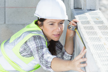 woman builder measuring a block