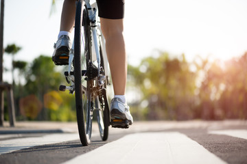 Athlete woman cyclist legs riding Mountain Bike on the road in the morning.