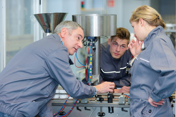 team of apprentices operanting a machine