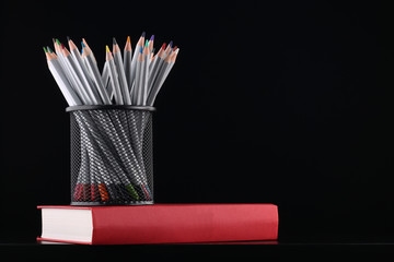 Color pencils in case and book on black background
