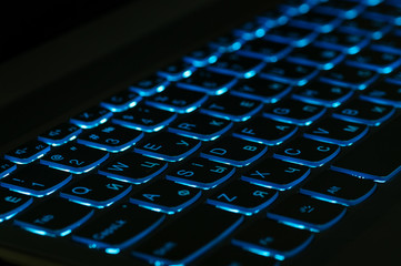 Blue backlight, backlit on gaming laptops computer in the dark. Close up.