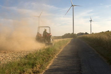farmer plowing his field infront of wind turbines