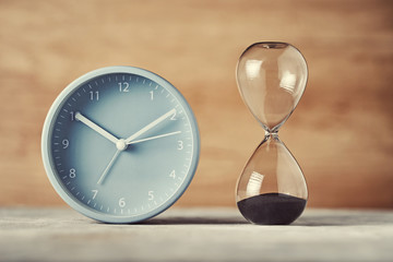 Hourglass and alarm clock on desk, closeup