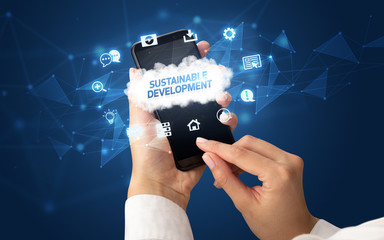 Female hand holding smartphone with SUSTAINABLE DEVELOPMENT inscription, cloud technology concept