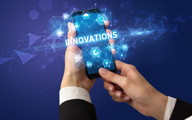 Female hand holding smartphone with INNOVATIONS inscription, modern technology concept