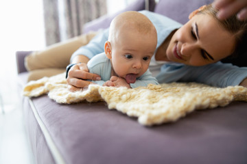 Smiling lady and cute child lying on sofa in living room