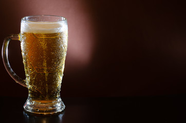 A misted glass of light beer on a dark background. Close-up, mock-up.