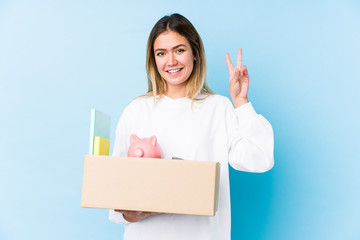 Young caucasian woman moving home isolated showing victory sign and smiling broadly.