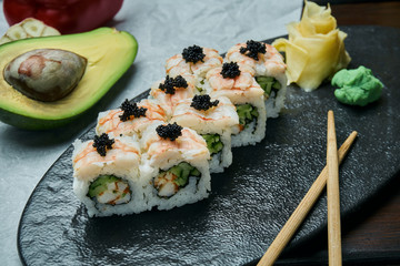 Classic japanese sushi rolls with shrimp, crab and caviar. California roll on a black plate with chopsticks. Japanese cuisine. Healthy seafood