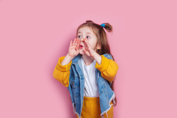 cute little girl with hands by mouth shouting on pink background