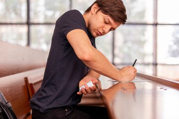 close up person sitting in lecture hall and cheating while passing the exam