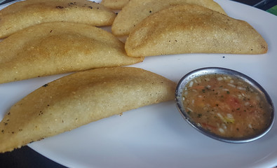 A plate with empanadas and sauce. The empanadas are a typical dish in Ecuador.