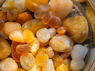 Small amber stone in a glass jar with water. Natural mineral. Alternative medicine.