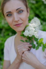 Beautiful girl is walking in the spring park near the trees in bloom. Spring season, sunny weather.