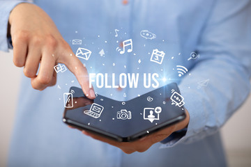 Businessman holding a foldable smartphone with FOLLOW US inscription, social media concept