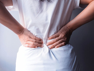 Thai Asian woman with lumbar pain backache massage on waist to relief