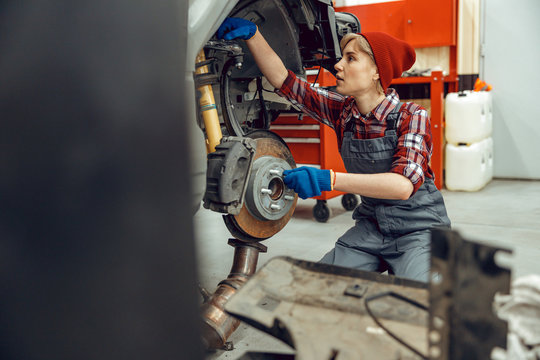 Focused young car mechanic checking brake pads