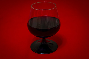 A glass of red wine on a background of red corduroy factory fabric