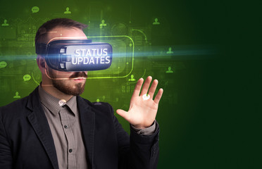 Businessman looking through Virtual Reality glasses with STATUS UPDATES inscription, social networking concept