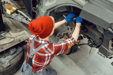 Young car mechanic inspecting the brake system