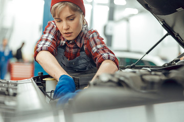 Serious young lady repairing a motor vehicle