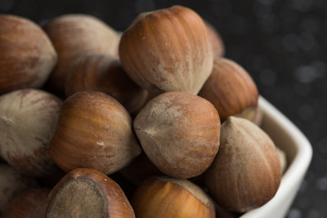 Hazelnuts in a white bowl dark background warm light close-up shot